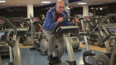 Spor salonunda çalışan bisikletli bir adamın görüntüleri.