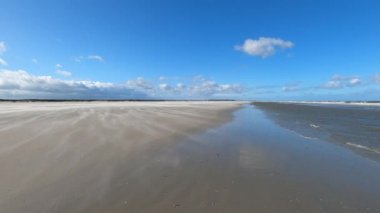 Hollanda 'daki Schiermonnikoog adasında bulut yansımaları ve büyük dalgalarla sahil ve deniz