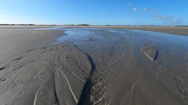 Hollanda 'daki Schiermonnikoog adasında bulut yansımaları ve büyük dalgalarla sahil ve deniz