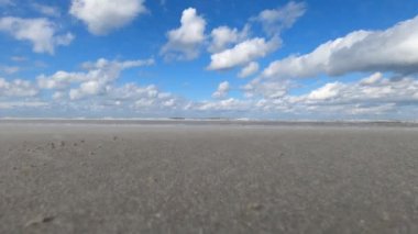 Hollanda 'daki Schiermonnikoog adasında bulut yansımaları ve büyük dalgalarla sahil ve deniz