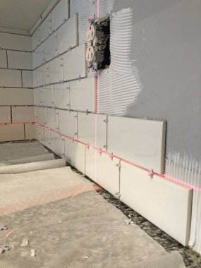 Beyaz duvar karoları bir elektrik prizine çevresinde bir lazer düzeyi ile kopya alanı kullanarak bir mutfak tezgahı üzerinde yükleme.