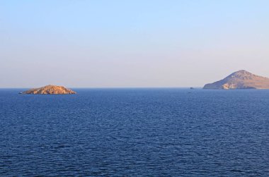 Bazı güzel mavi gökyüzü ve su kopya alanı bol olan küçük ıssız Yunan Adaları Ege Denizi'nin sakin açık suda binlerce dokulu bir arka plan.