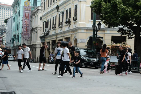 市内で最も人気のある広場の前で緑の光の上の道路を横断する人々 — ストック写真