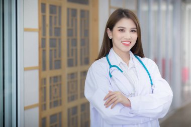 Kolları bağlı Asyalı bir kadın doktor. Beyaz bir bornoz ve steteskop giyiyordu. Coronavirus koruma kavramı.