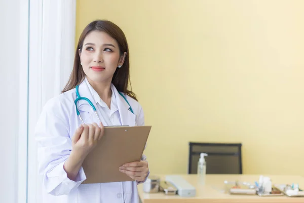 Una Hermosa Doctora Asiática Sonriendo Sosteniendo Portapapeles Mirando Por Ventana — Foto de Stock