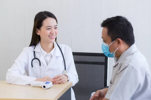 Asian woman doctor talk and encourage with a man patient to take care his health at hospital.