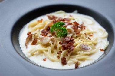 Beyaz soslu spagetti carbonara ve üstüne de çıtır pastırma ve maydanoz..