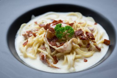 Beyaz soslu spagetti carbonara ve üstüne de çıtır pastırma ve maydanoz..