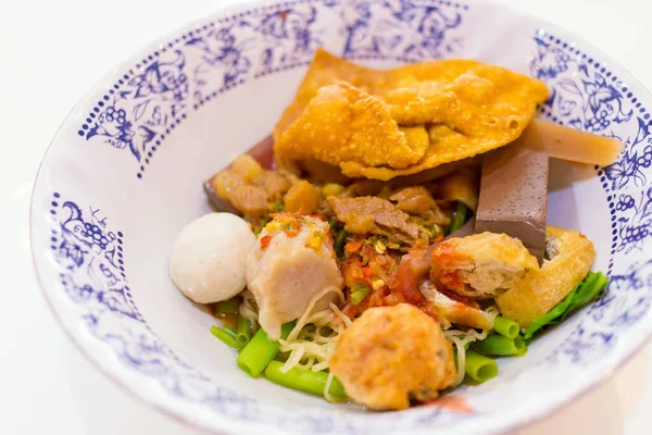 Fish ball noodles soup with red sauce (Yen Ta Fo) is a street food in Thailand. It contains fish balls, shrimp balls, fried tofu, fried dumplings, boiled chicken blood and vegetable which it put on a white background.