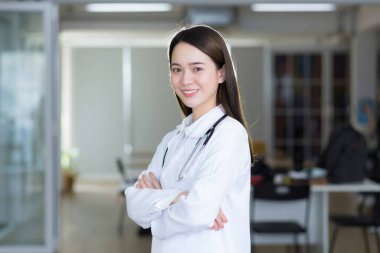 Kolları bağlı Asyalı bir kadın doktor. Beyaz bir bornoz ve steteskop giyiyordu.
