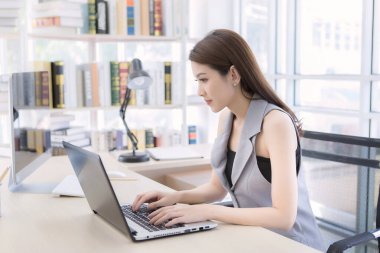 Asyalı kadın çalışıyor ve defterine masaj yapıyor. Corona virüsü salgınında evde çalışıyor..