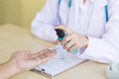 Coronavirus koruma konsepti. Doktor eli hastayı sterilize eder. Covid-19 enfeksiyonuna karşı önleyici önlemler. Kadın doktorun eli alkol spreyi kullanıyor..