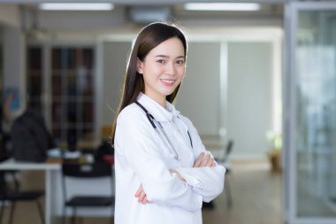 Kolları bağlı Asyalı bir kadın doktor. Beyaz bir bornoz ve steteskop giyiyordu.