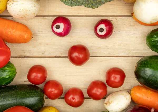 Frame of vegetables paprika, potatoes, onions, carrots, zucchini, mushrooms and radishes on a wooden background