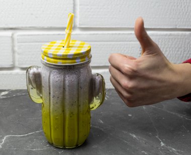 Kadın eli serin ve lezzetli bir milkshake gösteriyor.