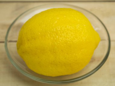 Ahşap arka planda cam bir tabakta limon