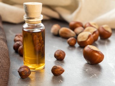 Şişede yağ ve mermer arka planda fındık.