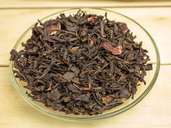 Dry hibiscus tea leaves in glass plate on wooden background