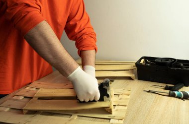 Tıbbi koruyucu maskeli bir adam, bir zımbayla ağaçla çalışır.