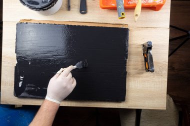 Bir adam arka plan için ahşap bir zemin boyuyor. Usta fotoğrafçılar için arka planlar yapar.