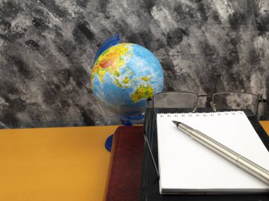 Gözlüklü kitaplar ve masa manzaralı bir küre..