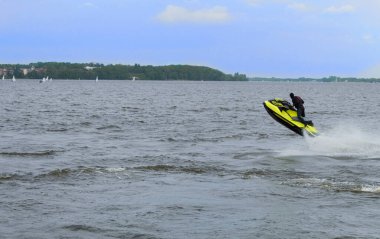 Tricks and jumps on a jet ski. A professional rider does tricks in the sea. A young man a professional jet ski performs many tricks on the waves. clipart