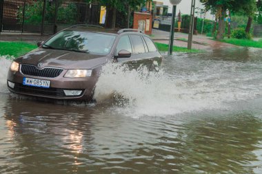 Varşova, Polonya - 21 Haziran 2020: Yol yağmurdan sonra sular altında kaldı. Otobüs yoğun yağmurdan sonra büyük bir su birikintisi ile yol boyunca seyahat eder. Yağmurdan sonra yolu su basmış.