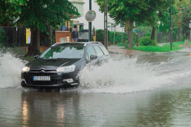 Varşova, Polonya - 21 Haziran 2020: Yol yağmurdan sonra sular altında kaldı. Otobüs yoğun yağmurdan sonra büyük bir su birikintisi ile yol boyunca seyahat eder. Yağmurdan sonra yolu su basmış.
