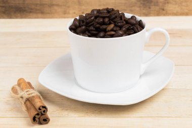 Beyaz fincan ve tahtadan bir arka planda kahve taneleri.