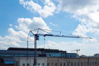 İnşaat malzemelerini kaldırmak için vinç. Evlerin ve gökyüzünün arka planında kule vinci