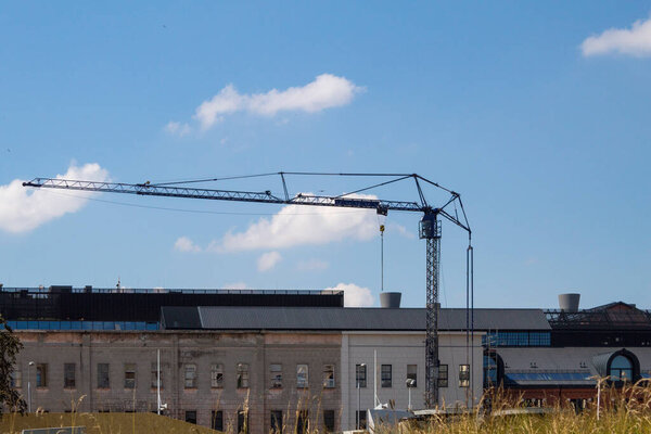 Crane for lifting building materials. Tower crane on the background of houses and sky