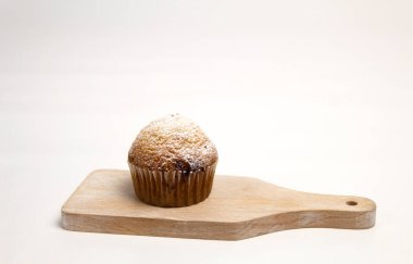 Metnin arka planı olarak küçük bir panoda kek. Kağıt kalıpta bir kek ve üzerine pudra şekeri serpilmiş.