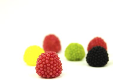 Beyaz arka planda farklı renklerde şekerleme. Çok renkli şekerler metin için arka plan olarak masaya saçılmıştır