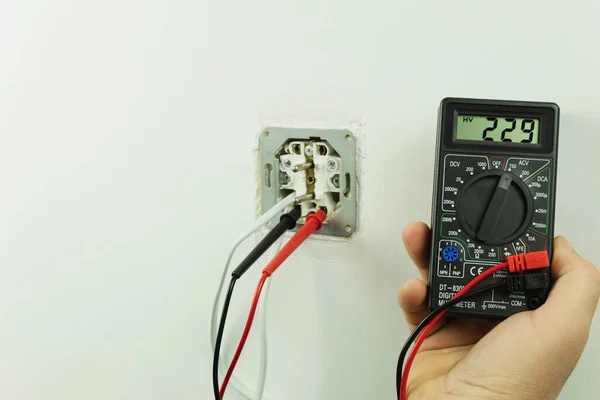 Measuring the voltage at the outlet. An electrician is repairing an outlet. Measuring the voltage in the socket with a tester