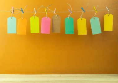 Arkaplan olarak farklı renklerde etiketler. Arkaplan olarak halat etiketleri. Etiketler çok renkli mandalların üzerinde asılı duruyor.