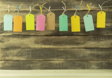 Arkaplan olarak farklı renklerde etiketler. Arkaplan olarak halat etiketleri. Etiketler çok renkli mandalların üzerinde asılı duruyor.