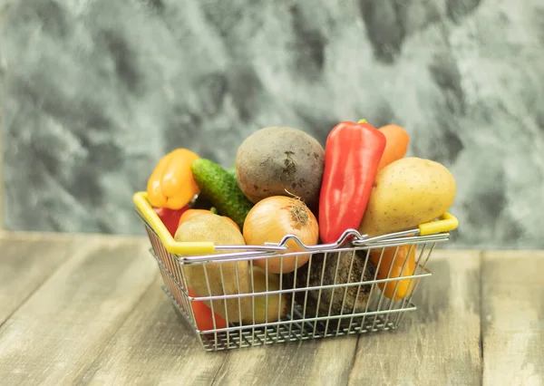 Fresh and healthy vegetables in the basket. Vegetables in an iron basket as a background with place for text. Fresh vegetables on the table and in the basket. Vegetables for vegetarians. Healthy petition