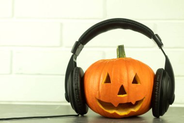 Mutfak masasında kulaklık olan bir balkabağı. Metin için yeri olan müzikal bir arkaplan fikri