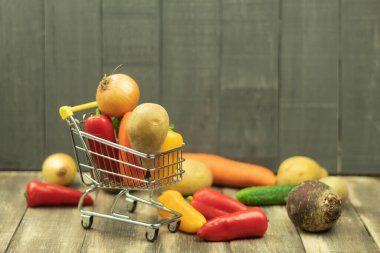 Alışveriş sepetinde taze sebzeler. Alış veriş arabasında taze sebzeler, ahşap bir arka planda metne yer var.