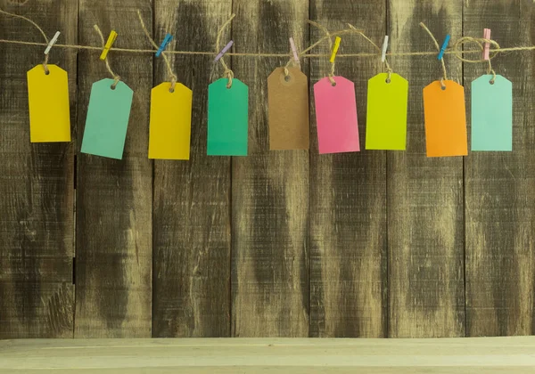 Labels in different colors as a background. Rope tags as background. The labels are suspended by a rope on multi-colored clothespins