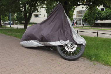 Motosiklet onu yağmurdan ve güneşten korumak için bir örtü ile kaplıdır. Motosikletleri ve motosikletleri ört.
