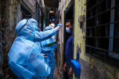 Mumbai, Hindistan / 17 Haziran 2020: Bir Corona virüsü kontrolü sırasında Ramabai Kolonisi, Ghatkopar East sakinlerinin sıcaklıklarını kontrol ederken sağlık çalışanları Kişisel Koruyucu Ekipman (PPE) takıyorlar.