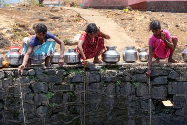 Maharashtra, Hindistan / 6 Mayıs 2016: Çocuklar, Dhakne köyü, Shahapur Taluka, Thane İlçesi 'ndeki neredeyse kuru bir kuyudan su getiriyor