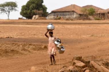 Maharashtra, Hindistan / 29 Mayıs 2018: Genç bir kız, Thane County, Shahapur Taluka 'daki neredeyse kuru bir kuyudan su getirmek için paslanmaz kaplar taşıyor.