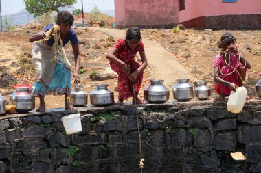Maharashtra, Hindistan / 6 Mayıs 2016: Çocuklar, Dhakne köyü, Shahapur Taluka, Thane İlçesi 'ndeki neredeyse kuru bir kuyudan su getiriyor