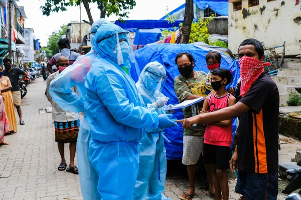 Mumbai, Hindistan / 17 Haziran 2020: Bir sağlık çalışanı Corona virüs tarama kampı sırasında Ghatkopar East 'teki Ramabai Ambedkar Nagar' ın varoşlarında yaşayan birinin sıcaklığını kontrol ediyor