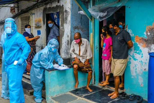 Mumbai, Hindistan / 17 Haziran 2020: Bir sağlık çalışanı Corona virüs tarama kampı sırasında Ghatkopar East 'teki Ramabai Ambedkar Nagar' ın varoşlarında yaşayan birinin sıcaklığını kontrol ediyor