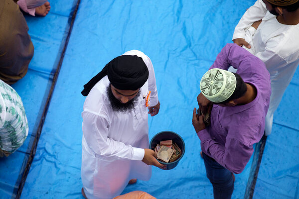 Мумбаи, Индия / 16 июля 2018 года: Человек собирает пожертвования во время молитвы Ид Аль Фитр за пределами станции Бандра
.