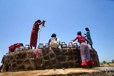Maharashtra, Hindistan / 6 Mayıs 2016: Kadınlar, Dhakne köyü, Shahapur Taluka, Thane İlçesi 'ndeki neredeyse kuru bir kuyudan su getiriyor