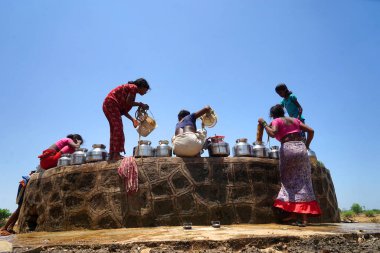 Maharashtra, Hindistan / 6 Mayıs 2016: Kadınlar, Dhakne köyü, Shahapur Taluka, Thane İlçesi 'ndeki neredeyse kuru bir kuyudan su getiriyor